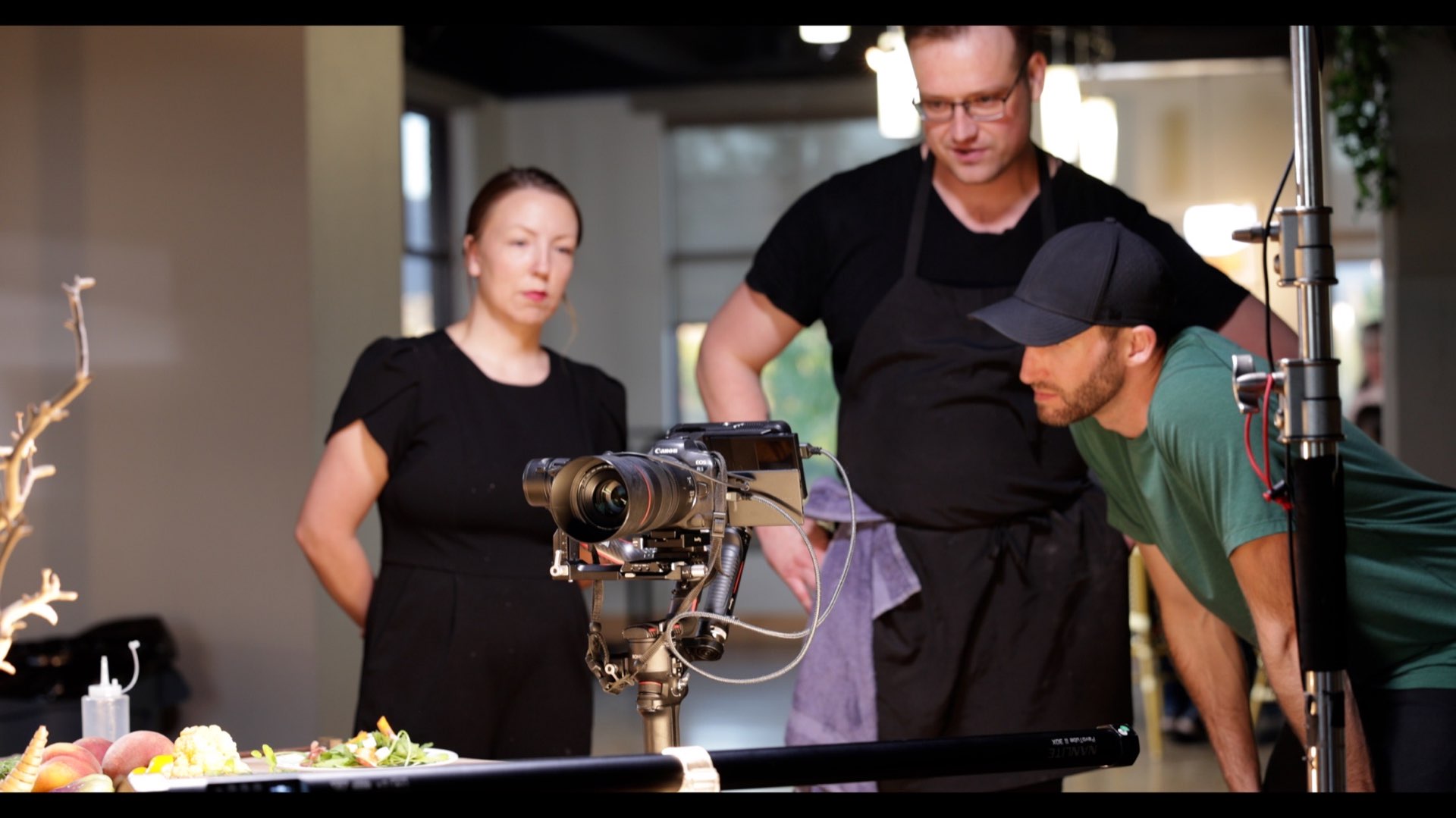 Behind-the-scenes production setup documenting food with camera, crew coordination, and controlled lighting